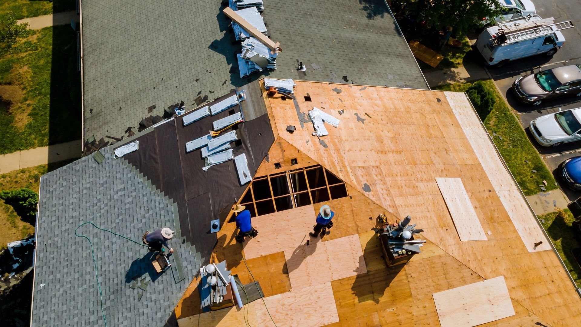 Aerial view of workers installing wooden roof shingles on a house