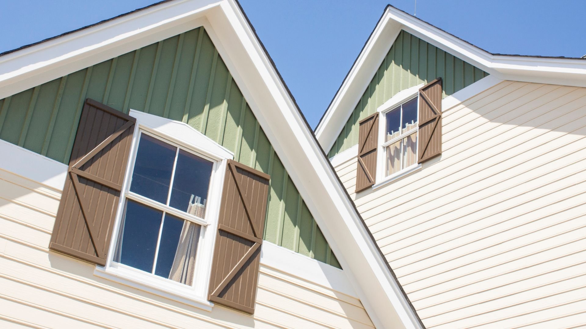 Green and white houses with wooden shutters and angled rooflines