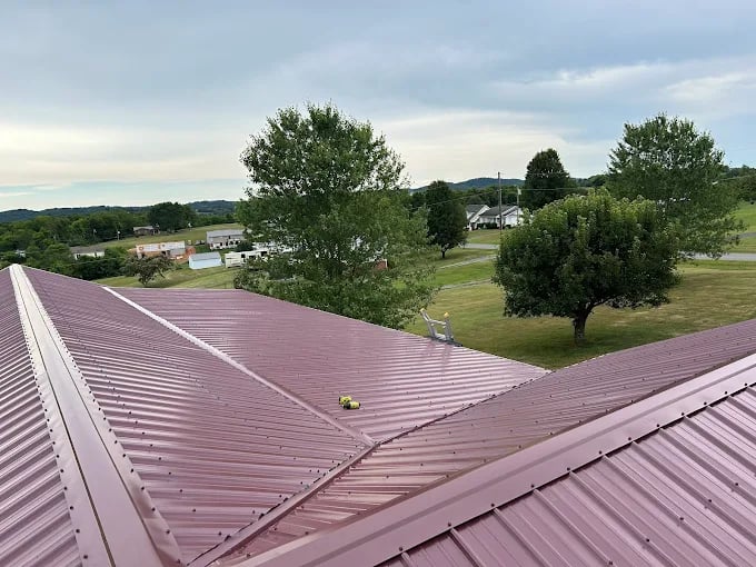 View from metal roof over rural landscape with trees and green fields