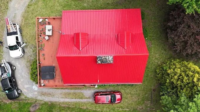 Aerial view of bright red building with vehicles on gravel path