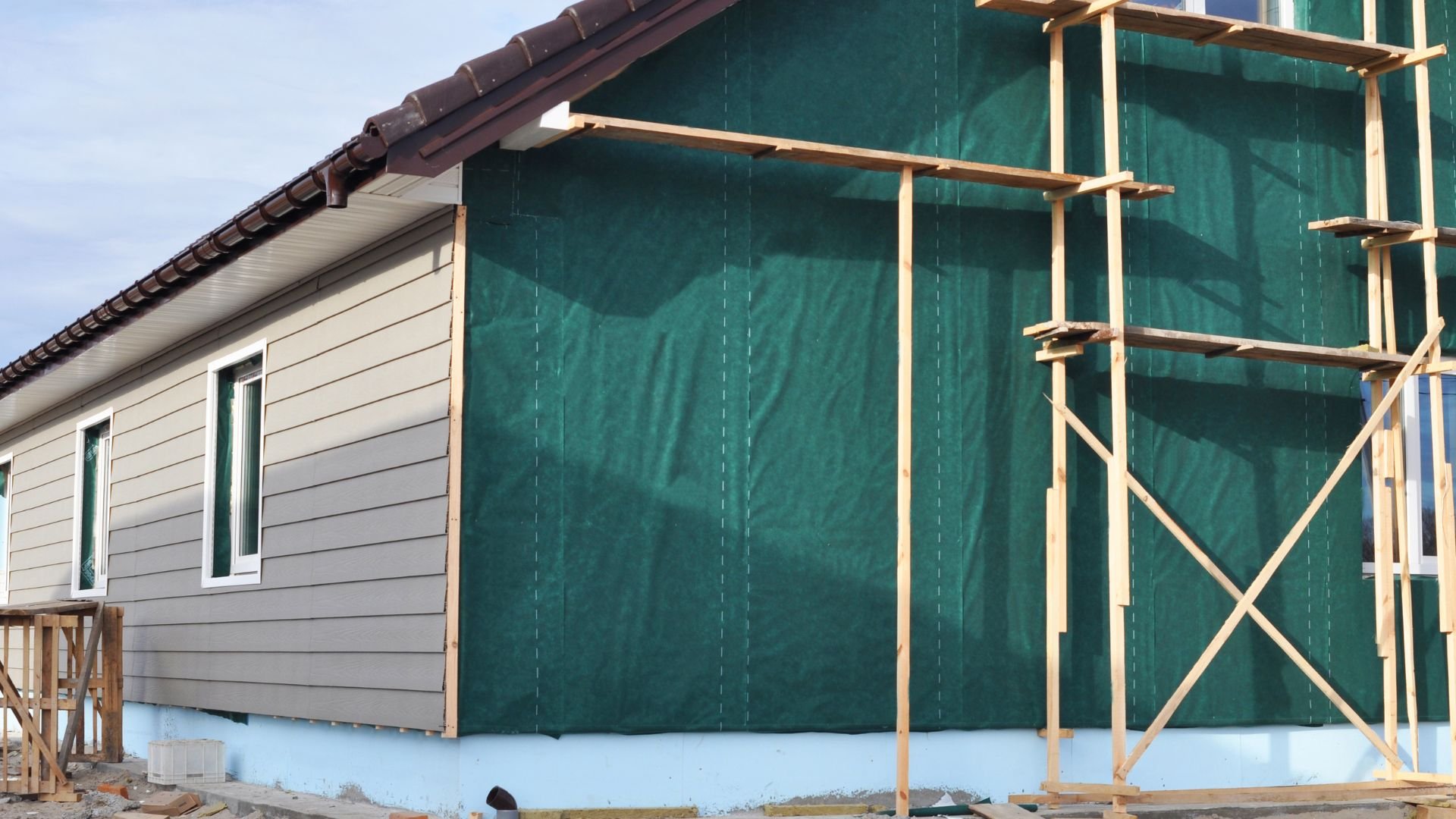 House under construction with green wrap and wooden scaffolding