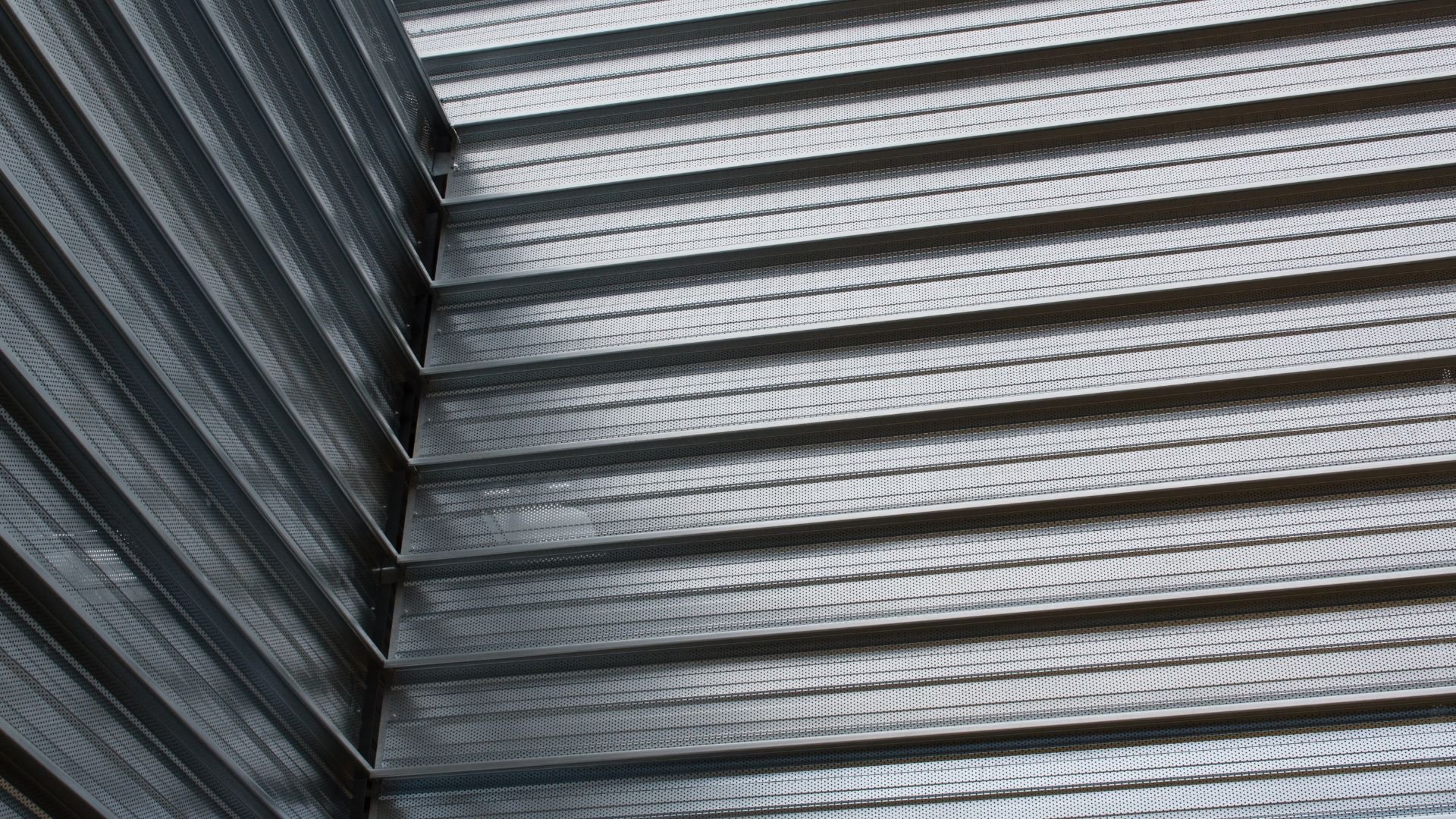 Perforated metal panels with repeating horizontal lines and shadows