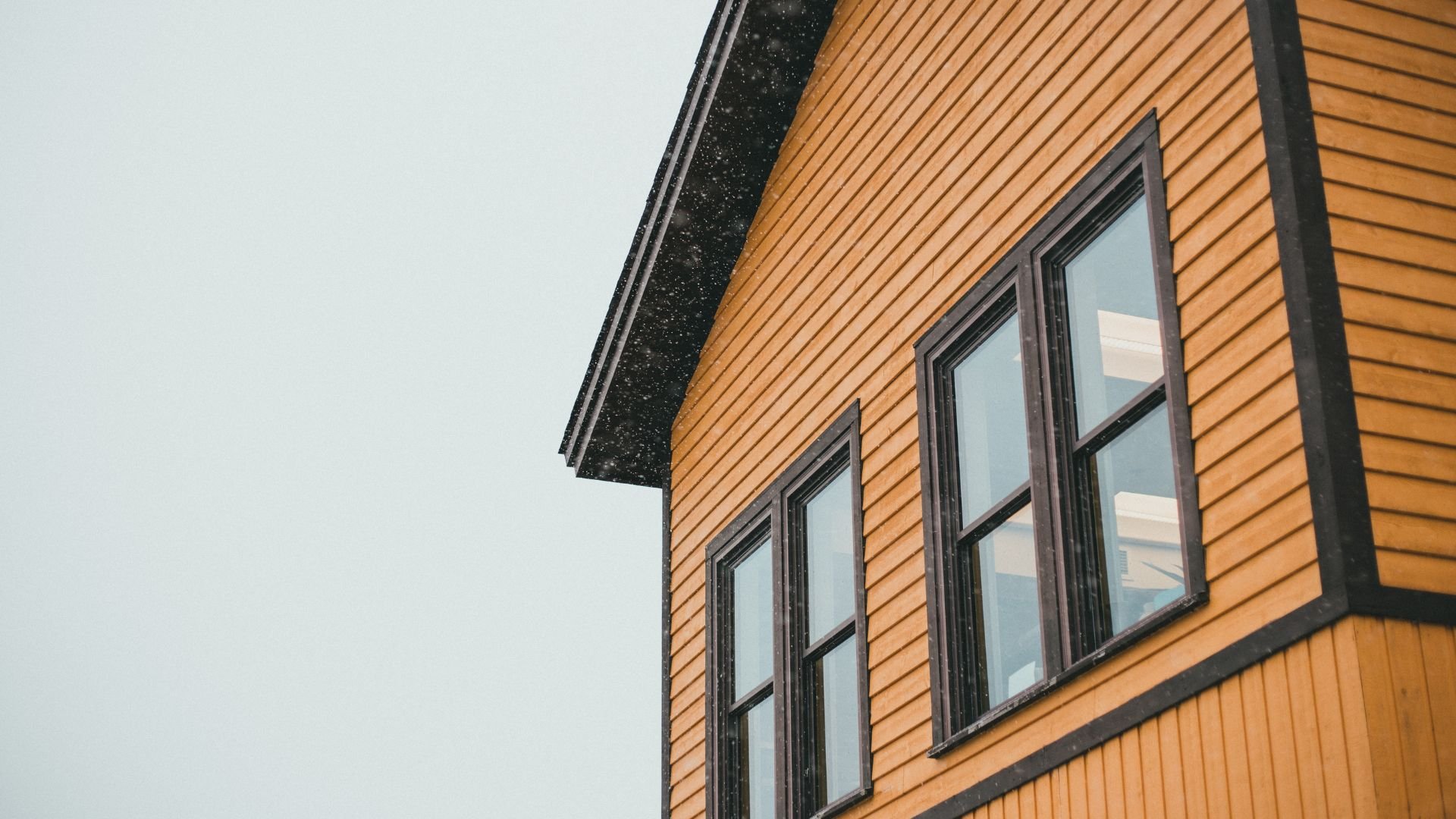 Wooden house exterior with large windows on a gray, snowy background