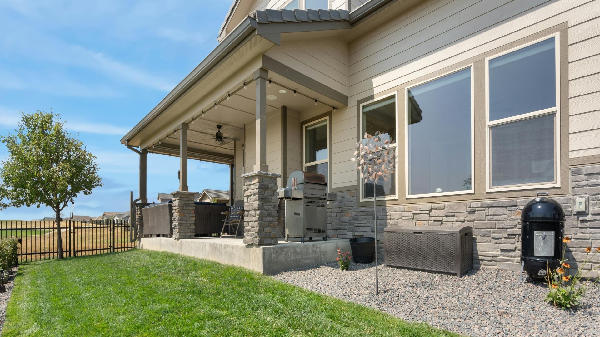 Modern suburban home with covered porch, manicured lawn, and outdoor living space