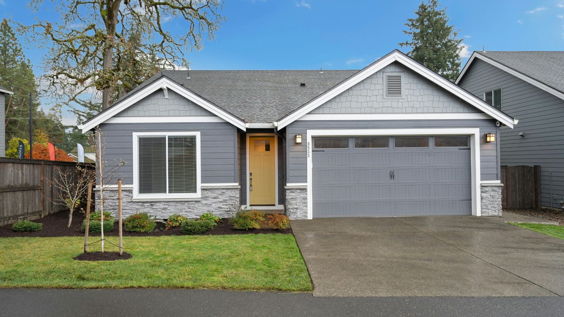 Modern gray house with yellow door and two-car garage on manicured lawn