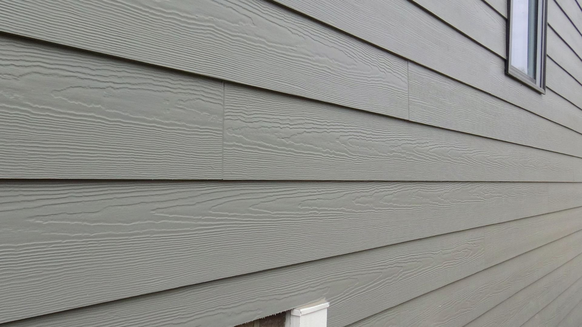 Gray horizontal wood-textured siding on a house exterior with window